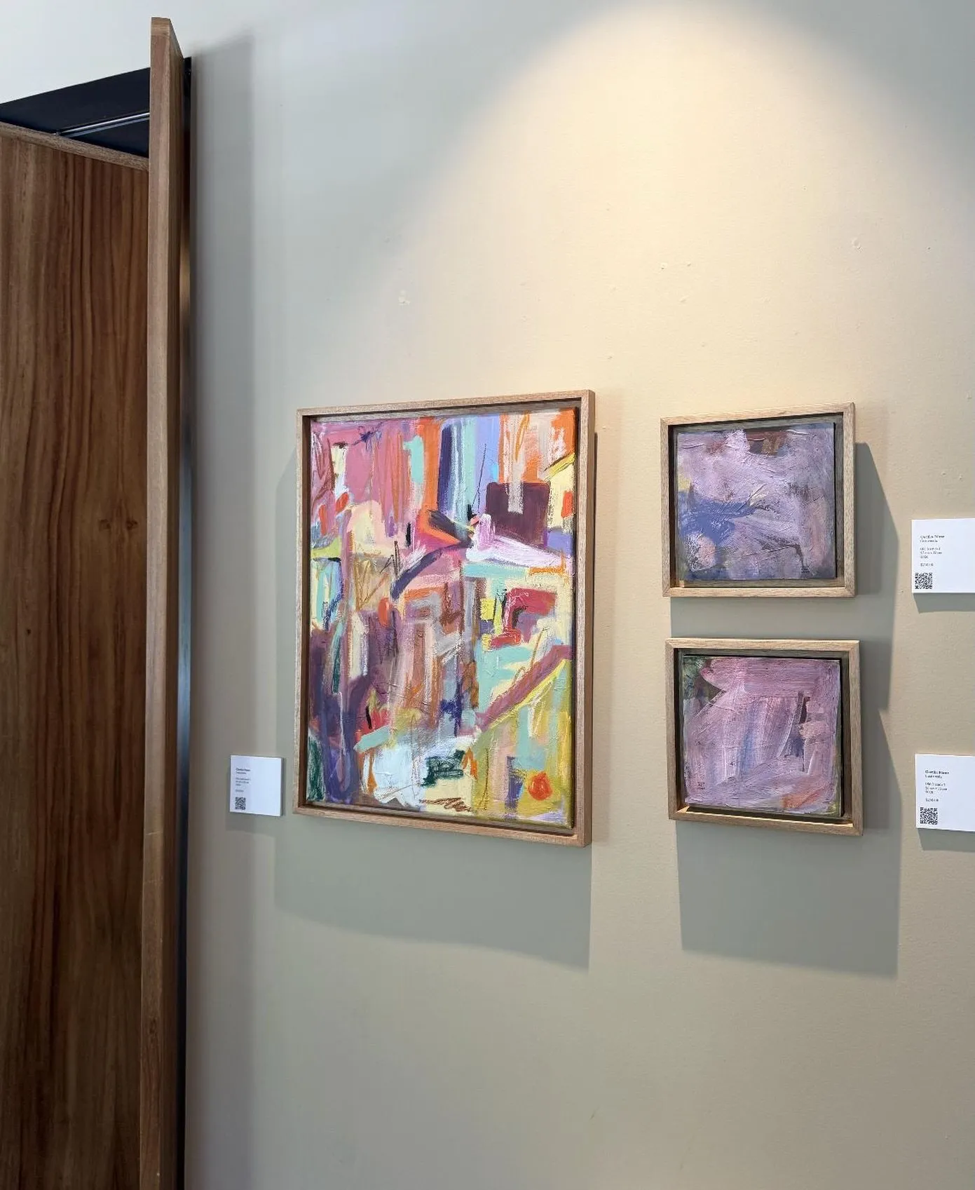 Tres pinturas abstractas de colores enmarcadas en madera, colgadas en una pared gris del restaurante