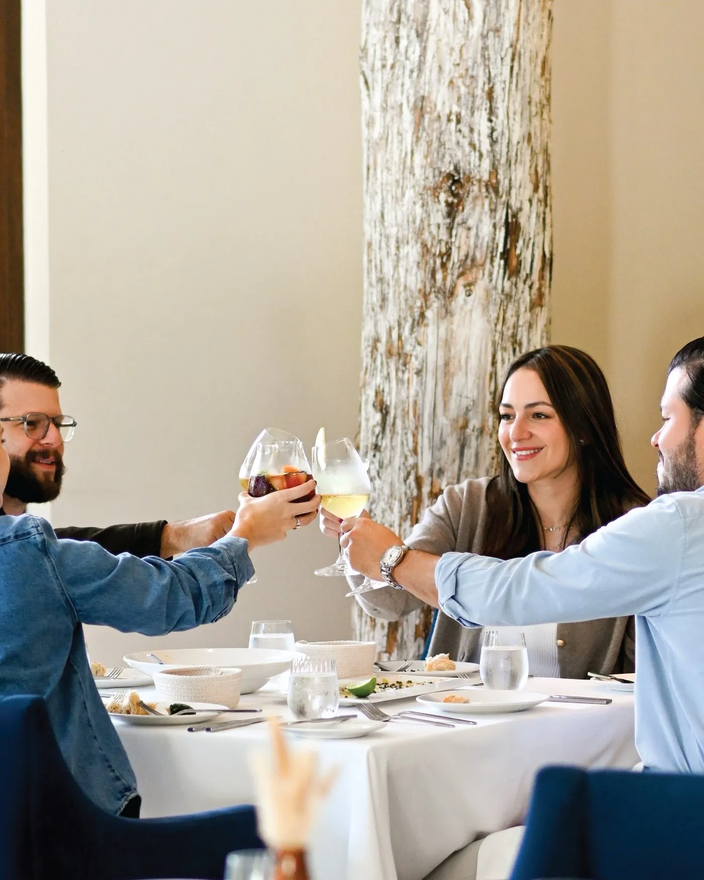 Tres comensales brindan con vino en una mesa del salón de Le Rendez Vous