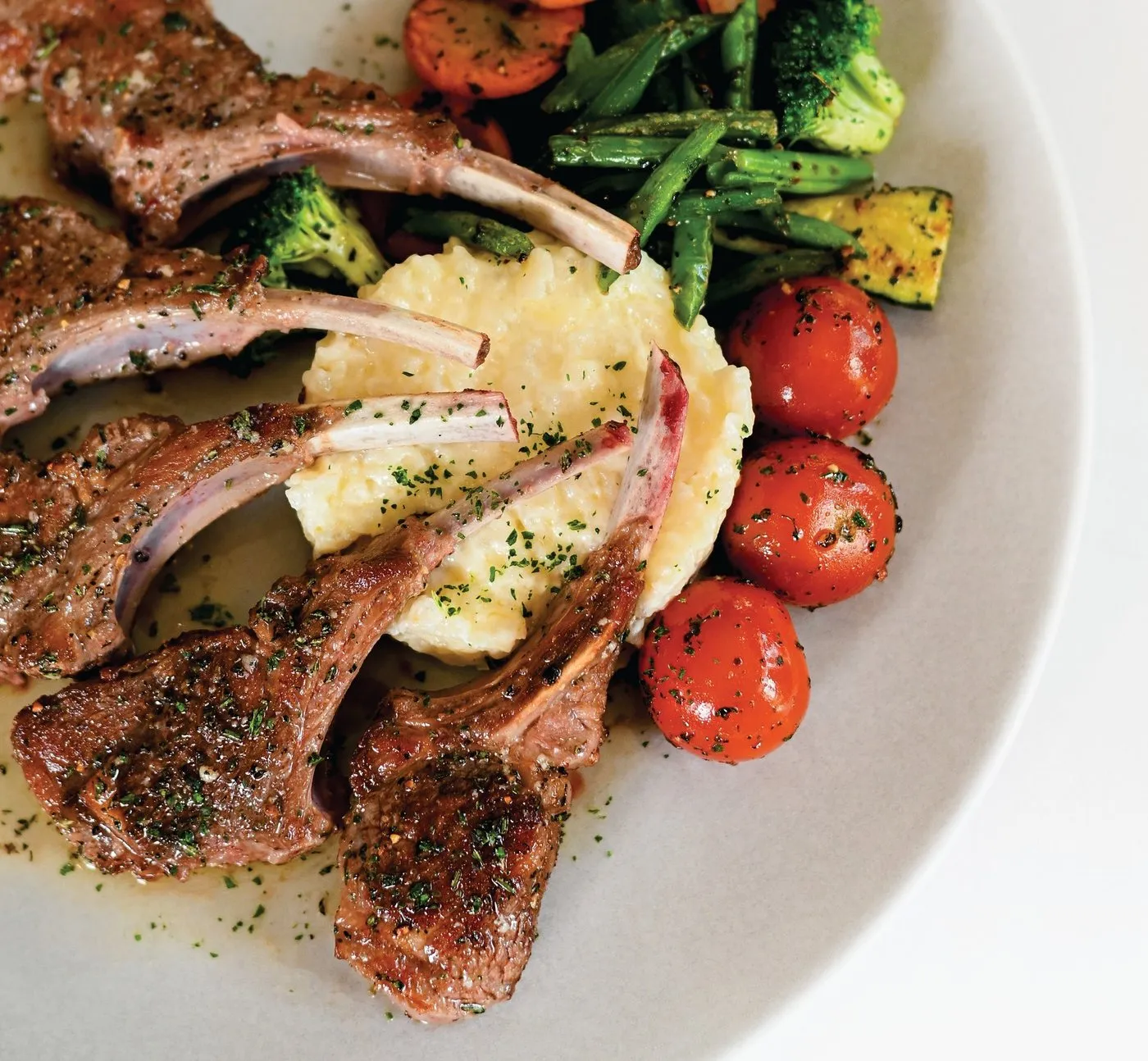 Costillas de cordero con tomates cherry, espárragos y puré