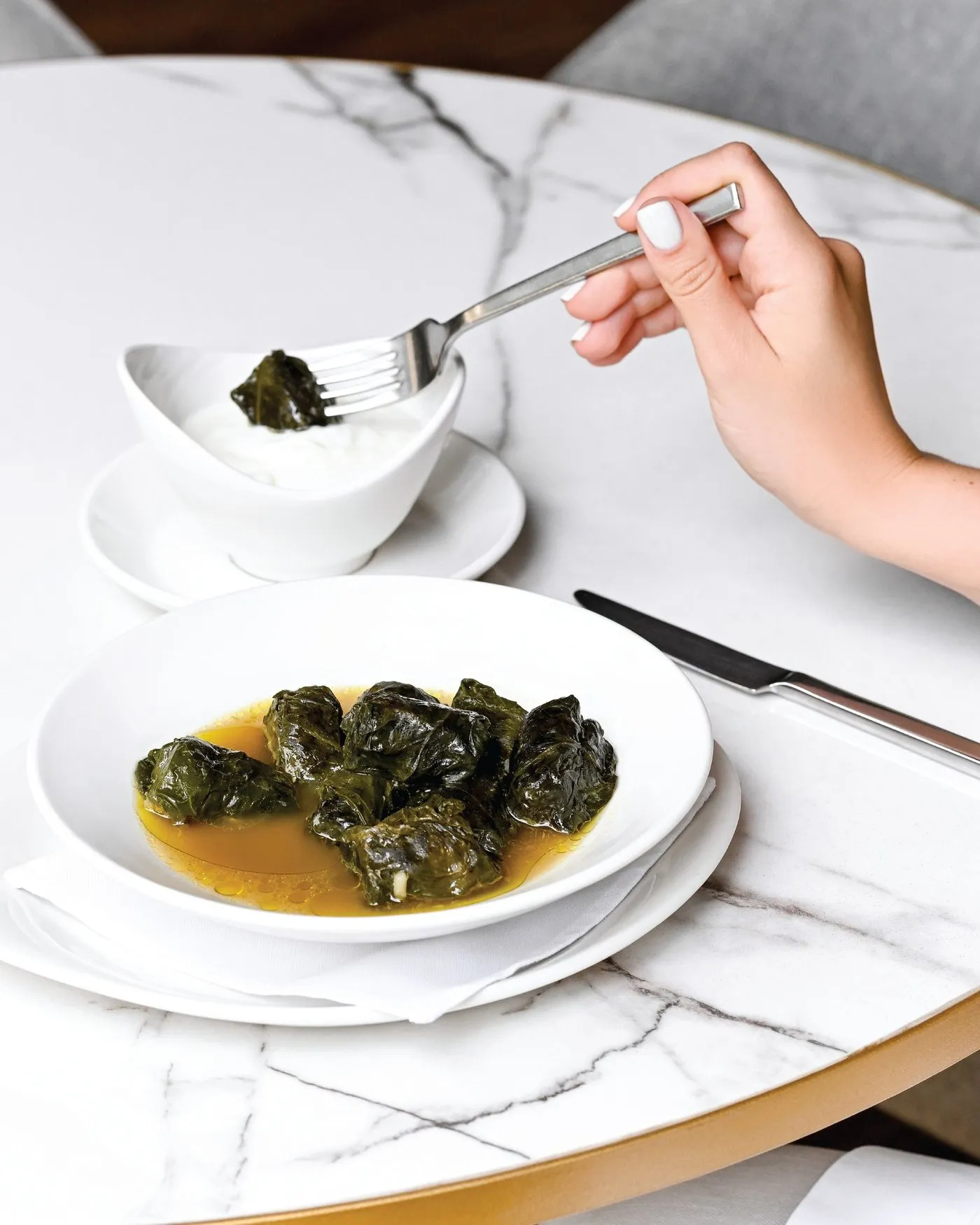 Dolmas de hoja de parra en caldo, servidas en un plato hondo blanco