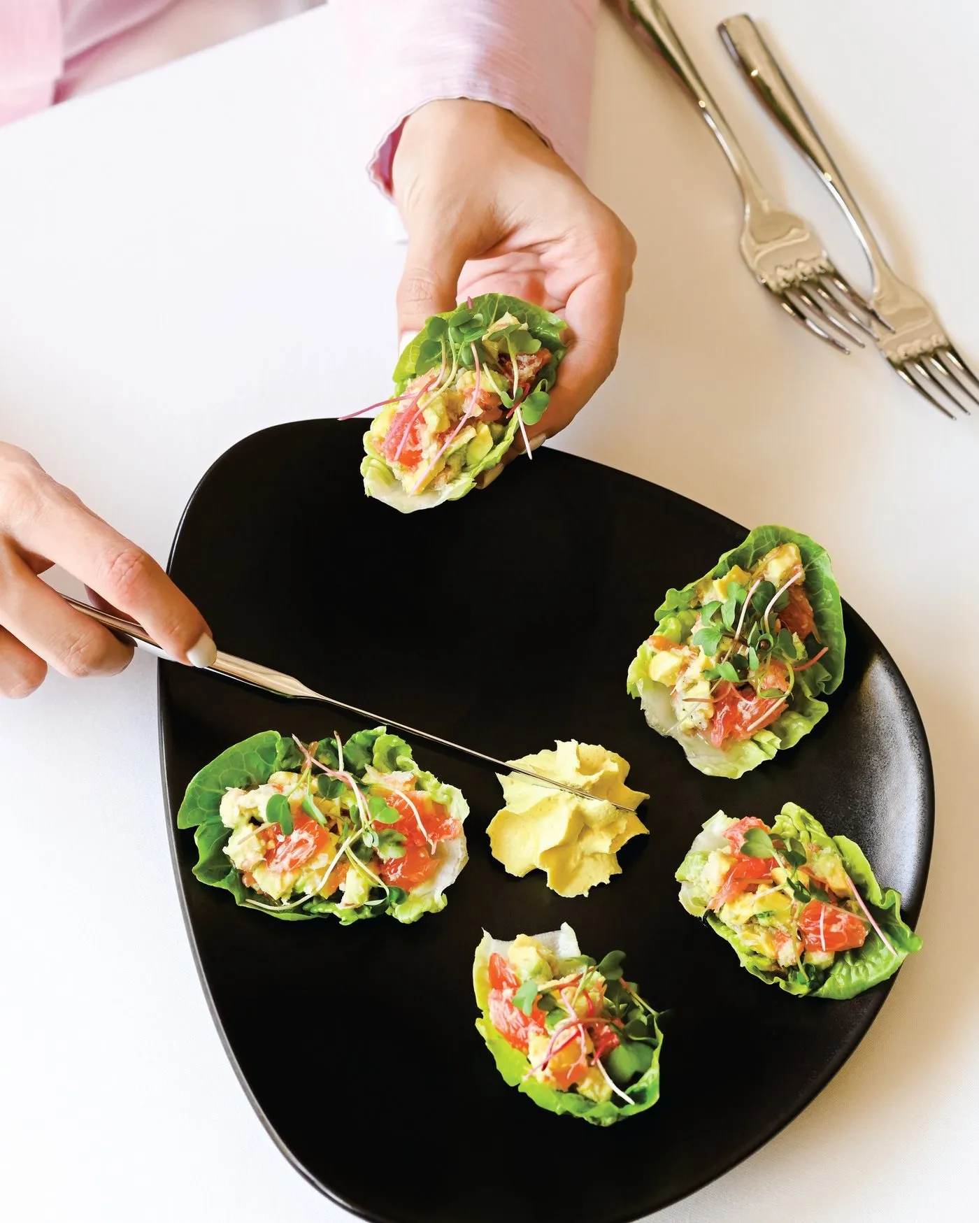 Ensalada de cangrejo servida en hojas de lechuga sobre un plato negro