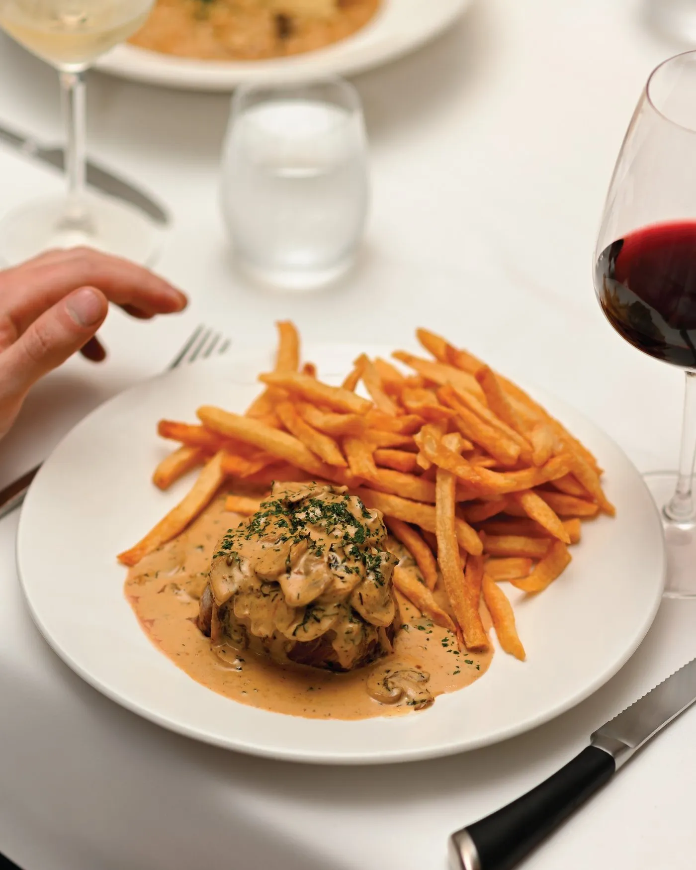 Steak en crema de hongos con papas fritas en plato blanco